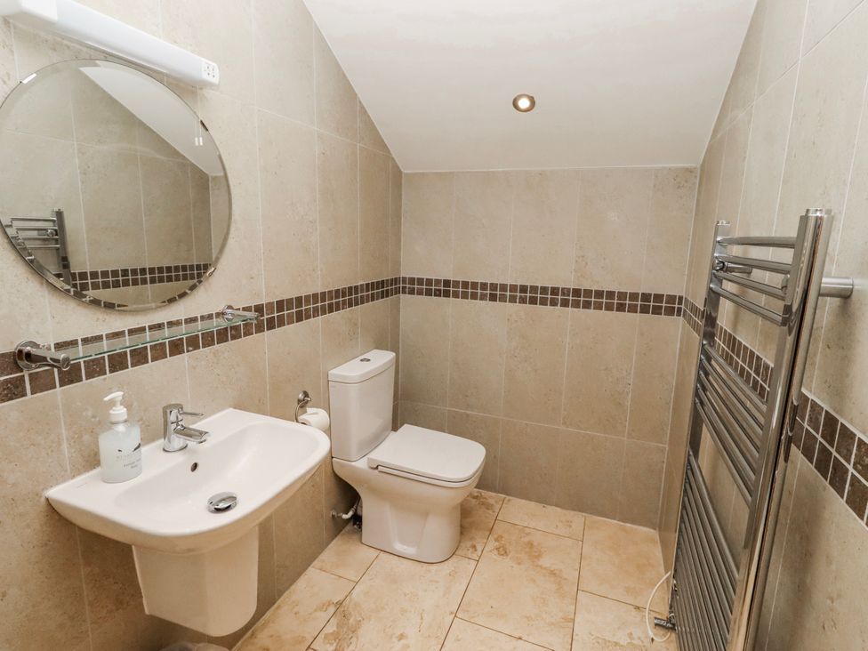 A bathroom with a sink, toilet, and mirror at Goosander in Bamburgh