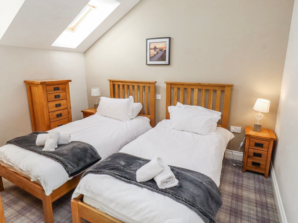 A bedroom with twin beds and wooden furniture at Goosander in Bamburgh