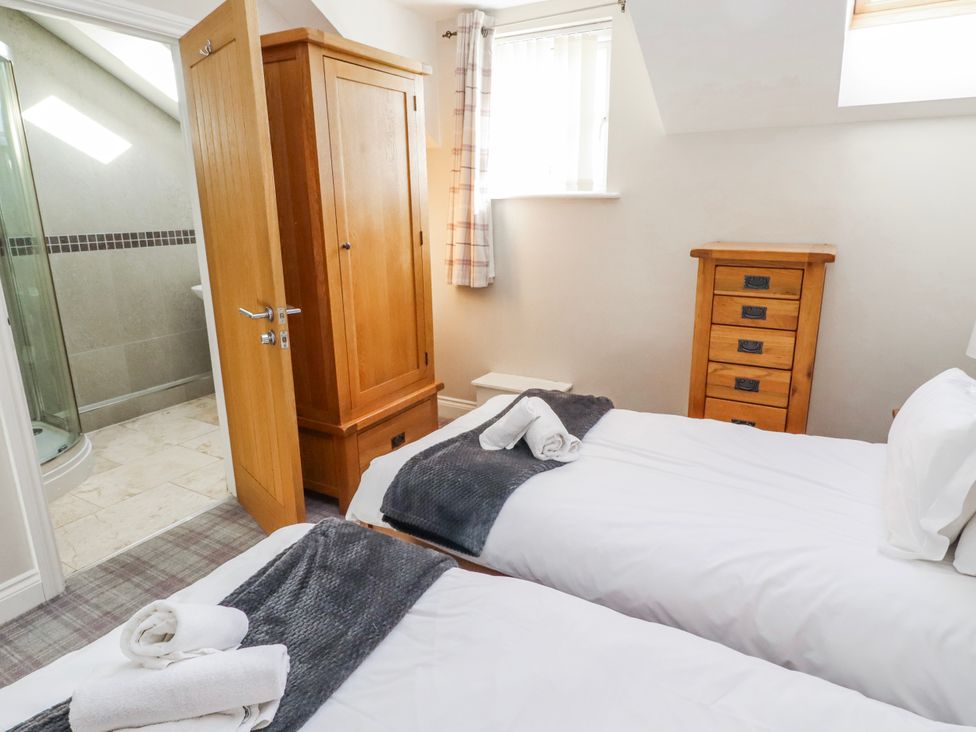 A bedroom with two beds and a wardrobe at Goosander in Bamburgh