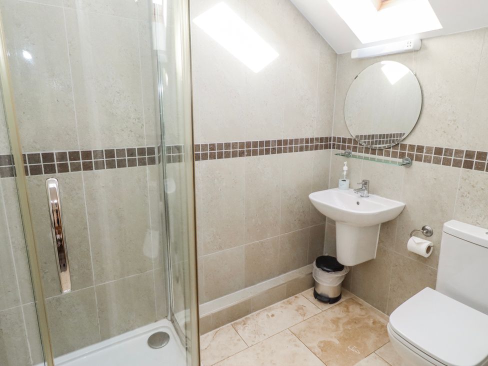 A bathroom with a shower, wash basin, and toilet at Goosander in Bamburgh