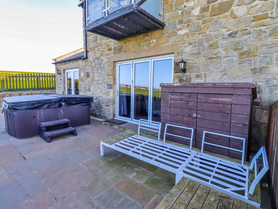 An outdoor area with a hot tub and patio furniture at Goosander in Bamburgh