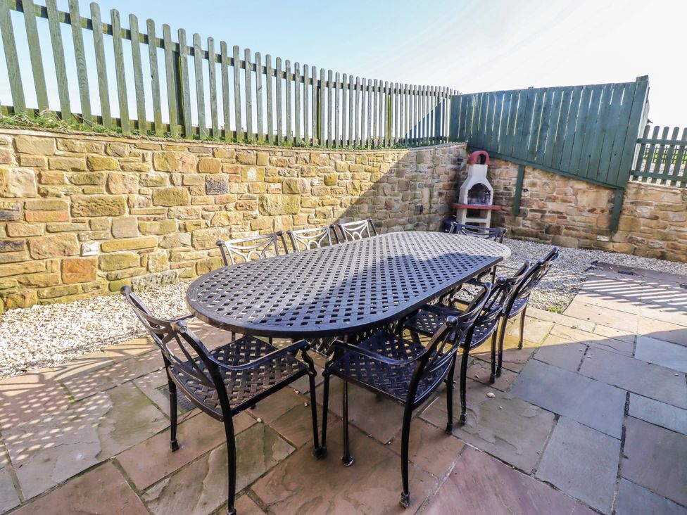An outdoor dining table with chairs in a garden at Goosander in Bamburgh