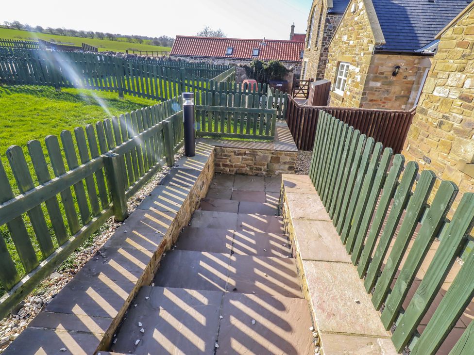 A garden area with a pathway and fence at Goosander in Bamburgh