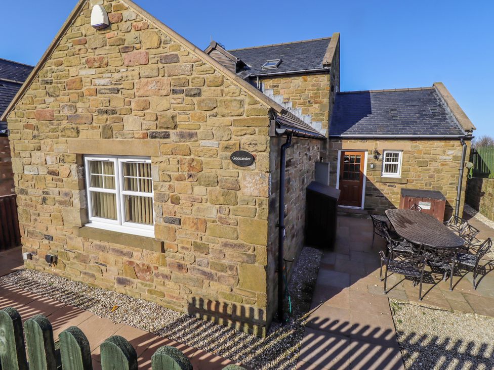An outdoor view of a stone property with a table and chairs at Goosander in Bamburgh