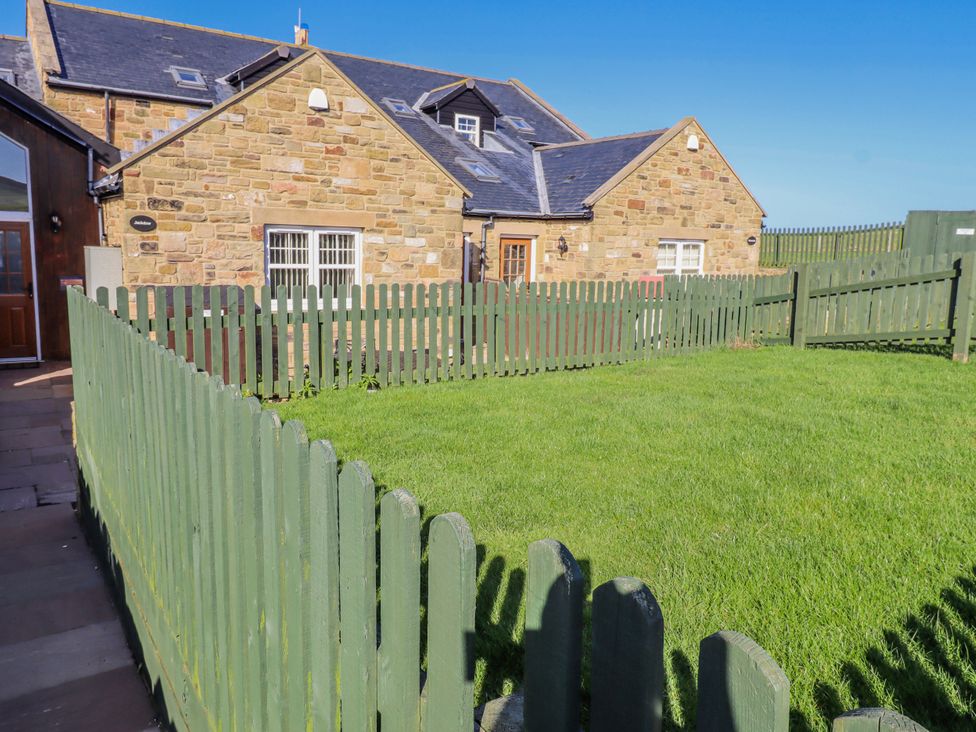 A stone house with a fenced yard at Jackdaw in Bamburgh