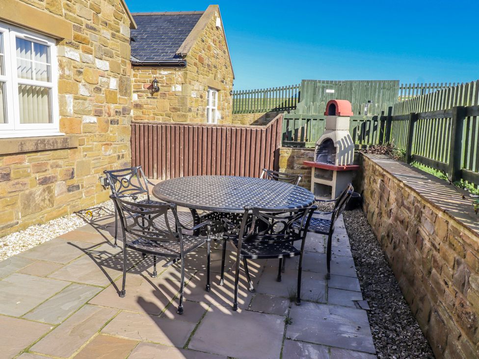 An outdoor seating area with a table and chairs at Jackdaw in Bamburgh