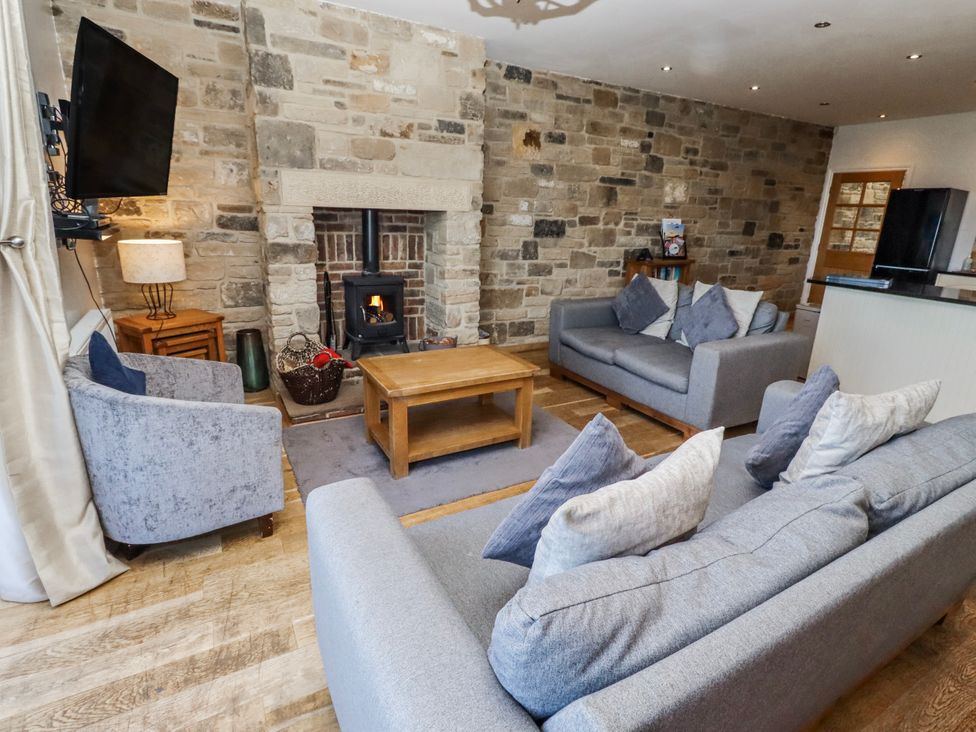 A living room with a fireplace and sofas at Jackdaw in Bamburgh