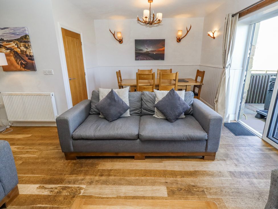 A living room with a sofa and dining area at Jackdaw in Bamburgh