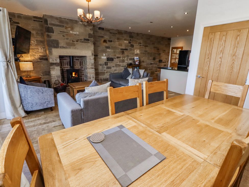 A living room with a sofa and dining area at Jackdaw in Bamburgh