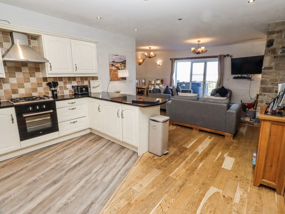 A kitchen with a living room area at Jackdaw in Bamburgh
