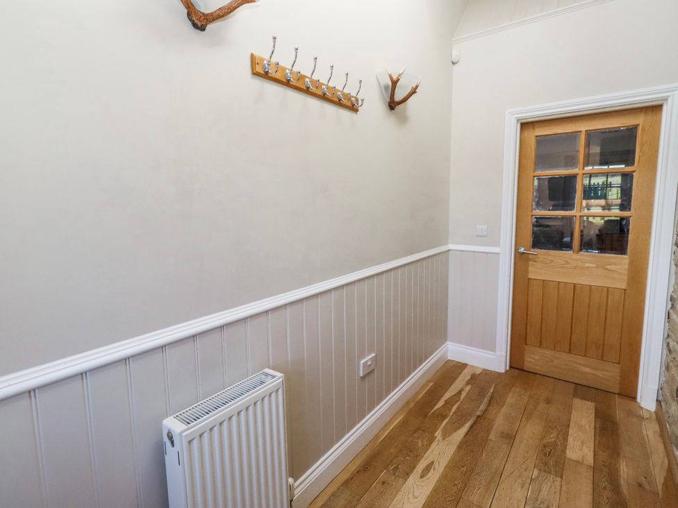 A hallway with hooks on the wall and a door at Jackdaw in Bamburgh