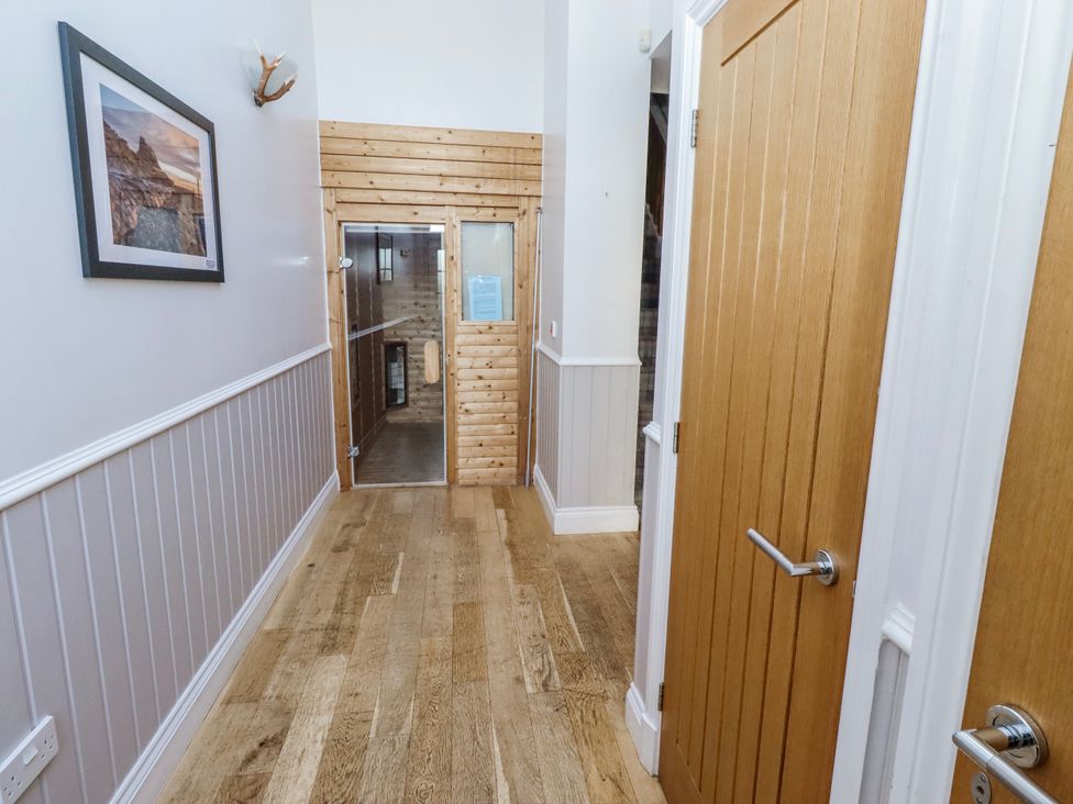 A hallway with wooden flooring and doors at Jackdaw in Bamburgh