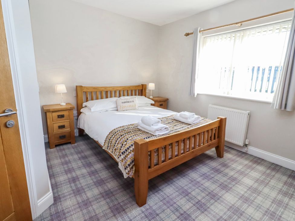 A bedroom with a bed and two bedside tables at Jackdaw in Bamburgh