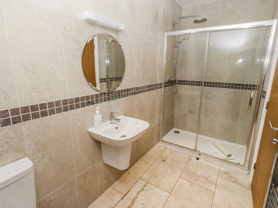A bathroom with a shower, sink, and toilet at Jackdaw in Bamburgh