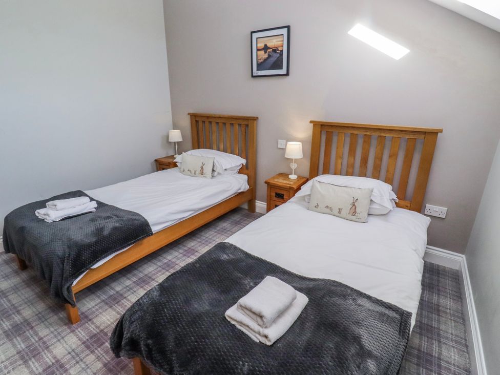 A bedroom with two single beds and a nightstand at Jackdaw in Bamburgh