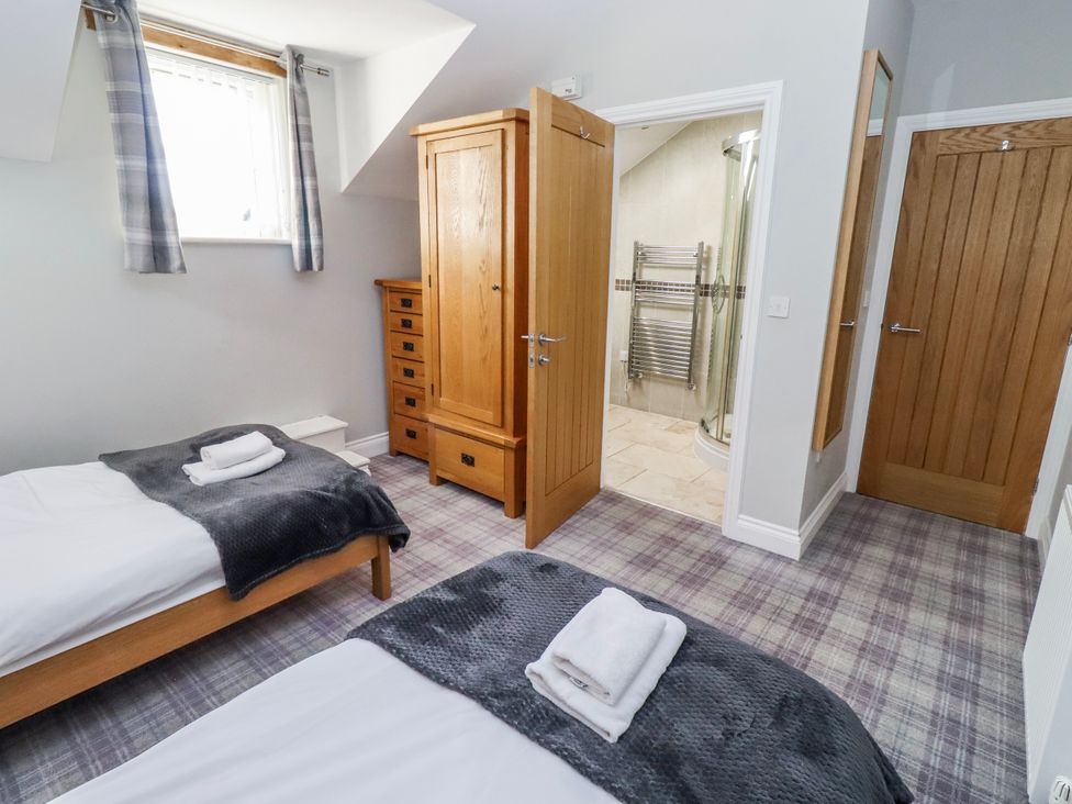 A bedroom with twin beds and a dresser at Jackdaw in Bamburgh