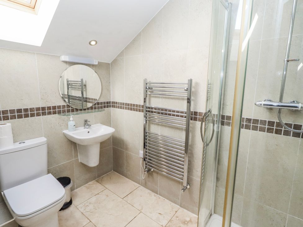 A bathroom with a shower, sink, toilet, and towel radiator at Jackdaw in Bamburgh