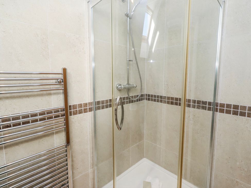 A shower enclosure with tiles and towel rail at Jackdaw in Bamburgh