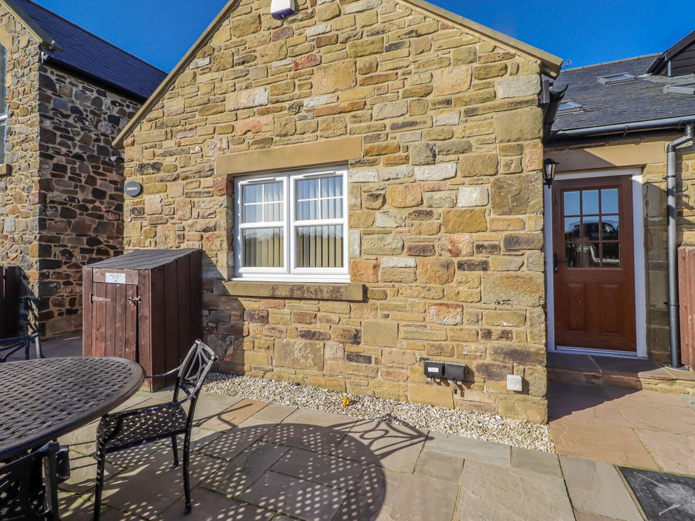 An outdoor area with a stone wall and table at Jackdaw in Bamburgh
