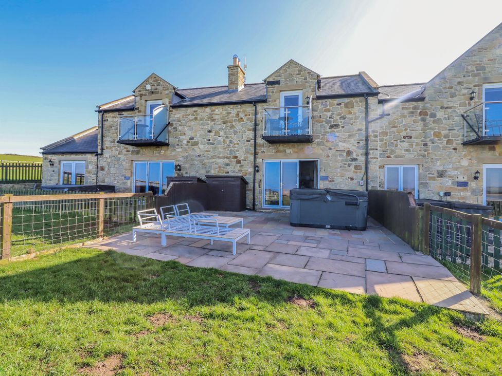 An outdoor patio with a hot tub and seating area at Jackdaw in Bamburgh