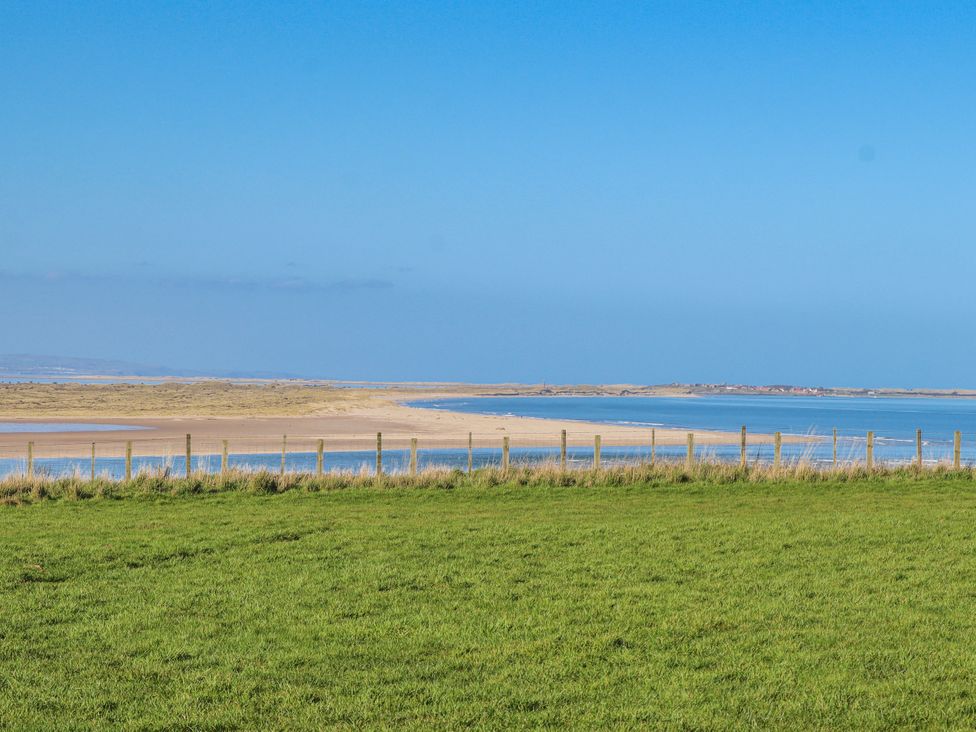 A view of water and sand from a field at Jackdaw in Bamburgh
