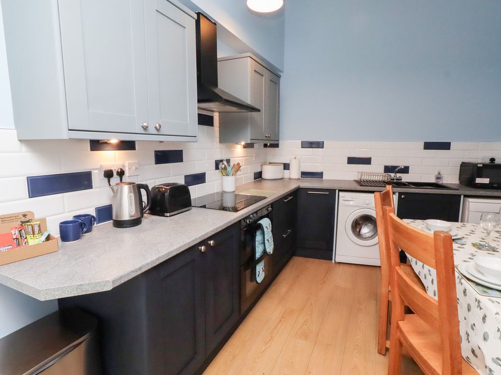 A kitchen with appliances and dining table at Riverside Cottage in Warkworth
