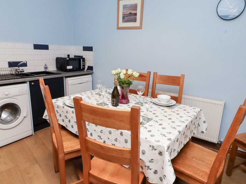 A kitchen with a dining table and chairs at Riverside Cottage in Warkworth
