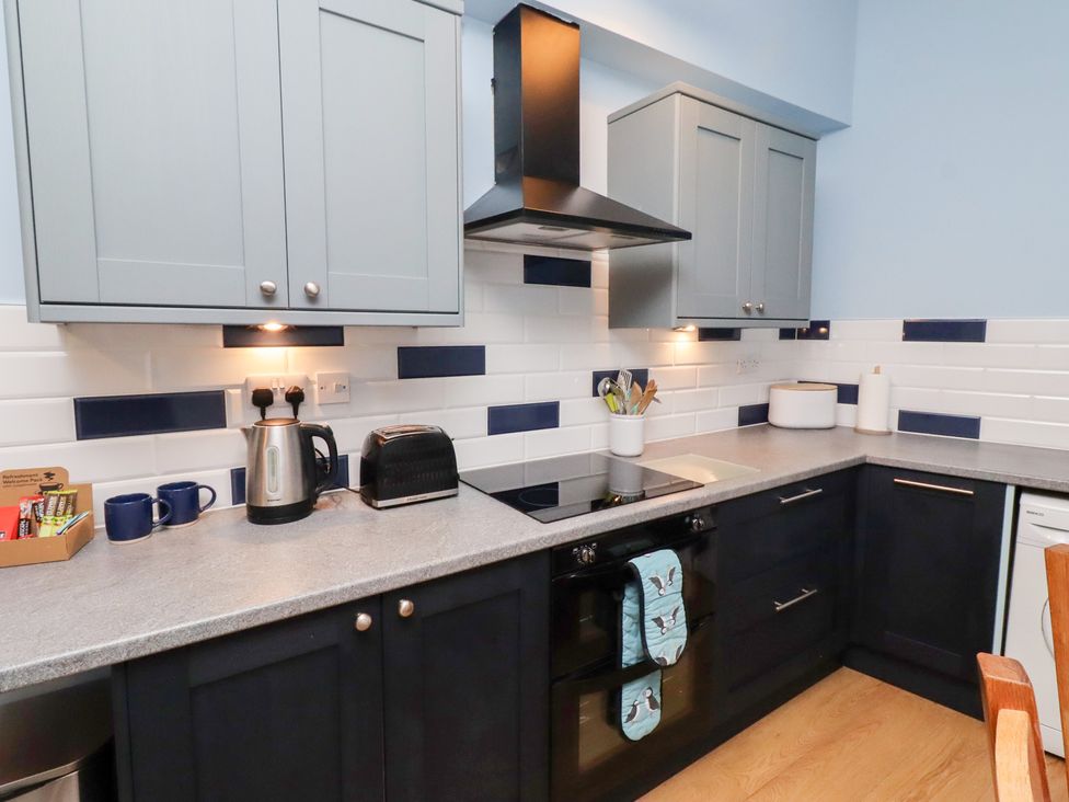 A kitchen with cabinets and appliances at Riverside Cottage in Warkworth