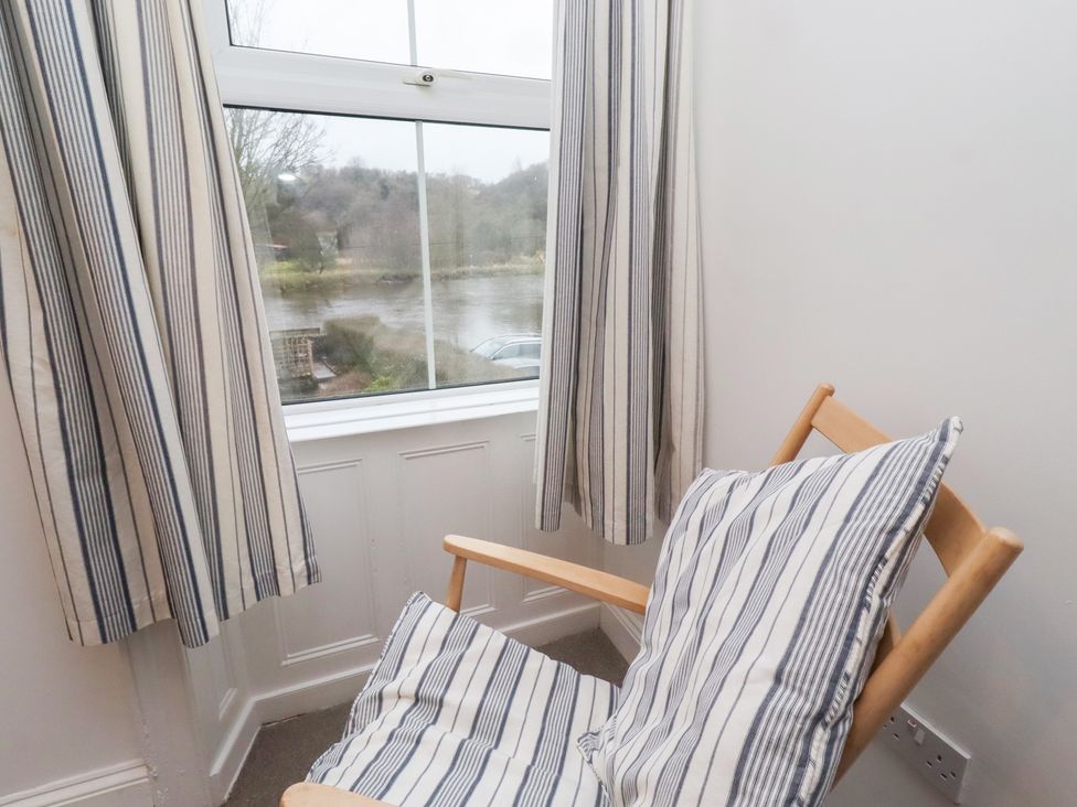 A sitting room with a chair and window view at Riverside Cottage in Warkworth