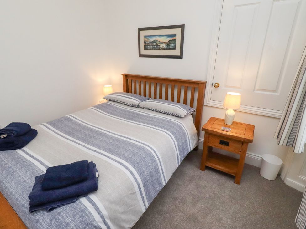 A bedroom with a bed and nightstand at Riverside Cottage in Warkworth
