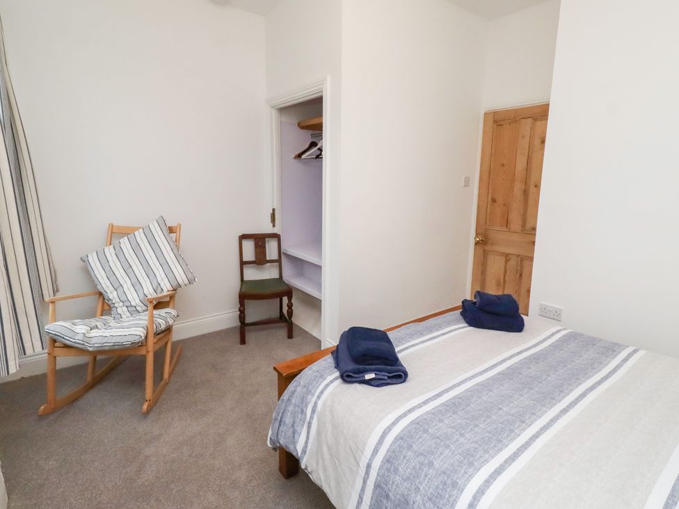 A bedroom with a bed and a rocking chair at Riverside Cottage in Warkworth