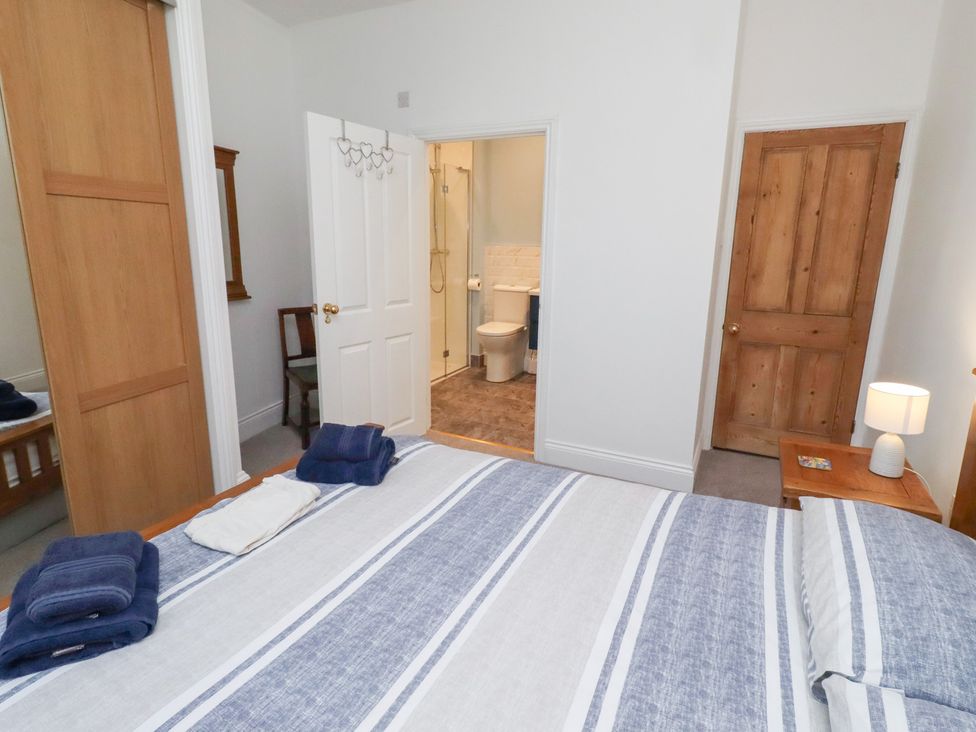 A bedroom with a bed and a bathroom doorway at Riverside Cottage in Warkworth