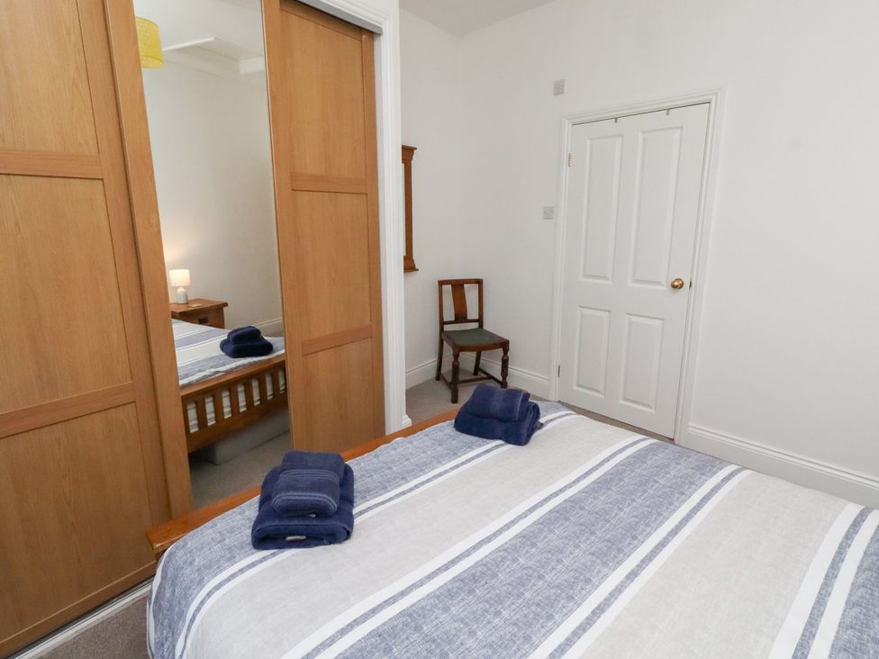 A bedroom with a bed and wardrobe at Riverside Cottage in Warkworth