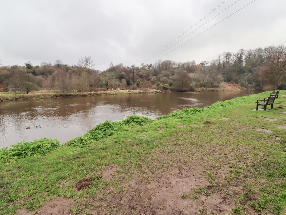 A river with grass and benches near the bank at Riverside Cottage in Warkworth