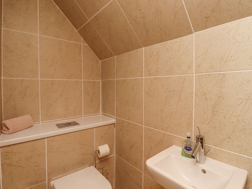 A small bathroom with a wall-mounted toilet and a sink with hand soap at Jara in Bamburgh