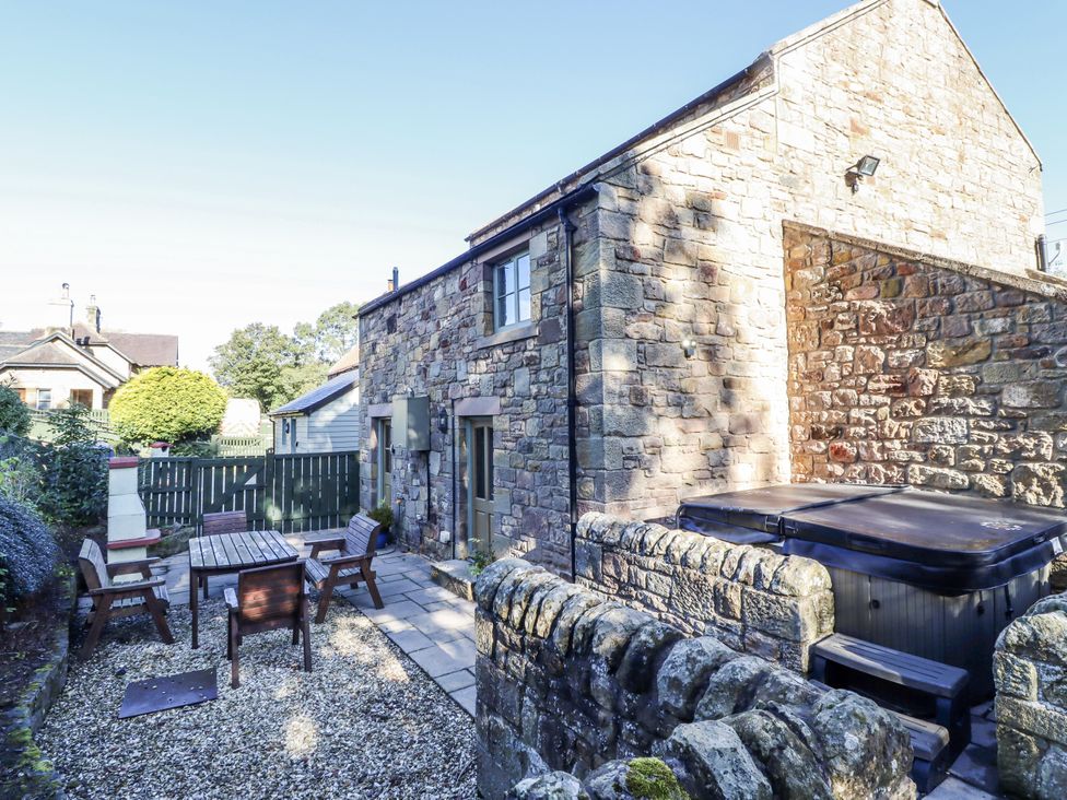 A garden with a dining table and hot tub at Old Mill in Lucker