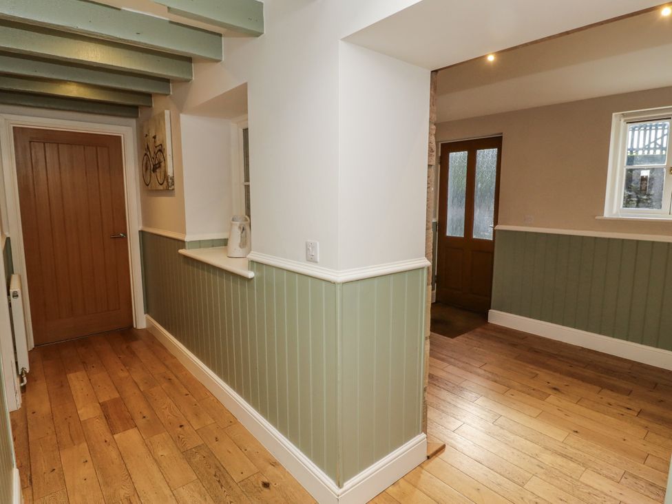 A hallway with wooden floor and green panels at Millstone in Lucker
