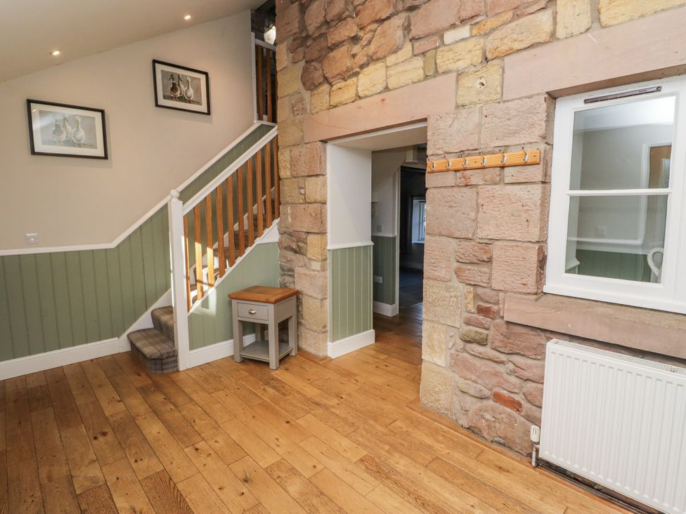 A hallway with a staircase and side table at Millstone in Lucker