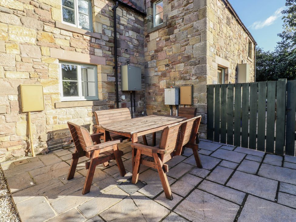 An outdoor seating area with a wooden table and chairs at Millstone in Lucker