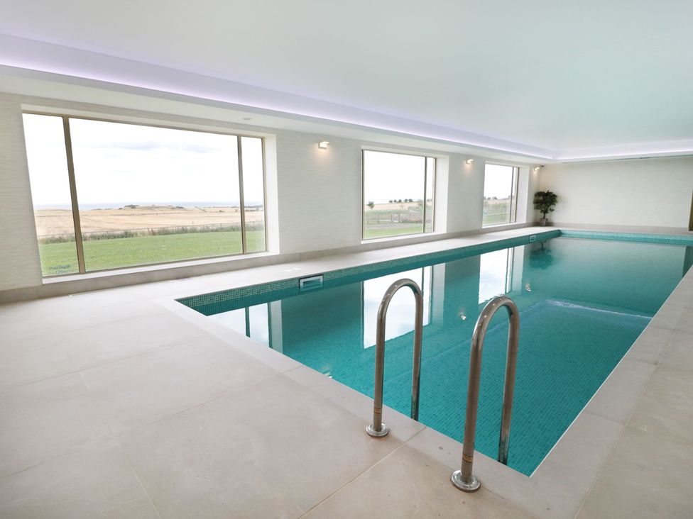 An indoor swimming pool with windows and a plant at Smithy Cottage in Embleton