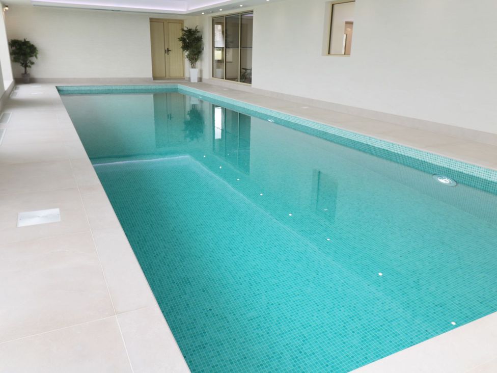 An indoor pool with tiled floor and doors at Bothy Cottage Embleton