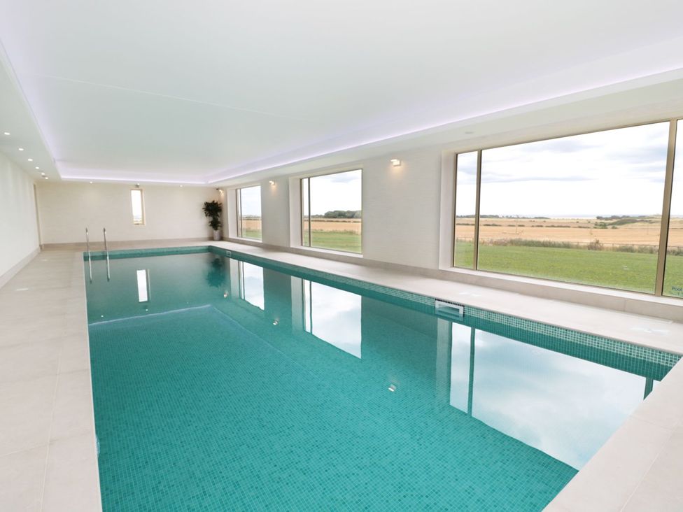 An indoor pool with windows overlooking a field at Bothy Cottage in Embleton