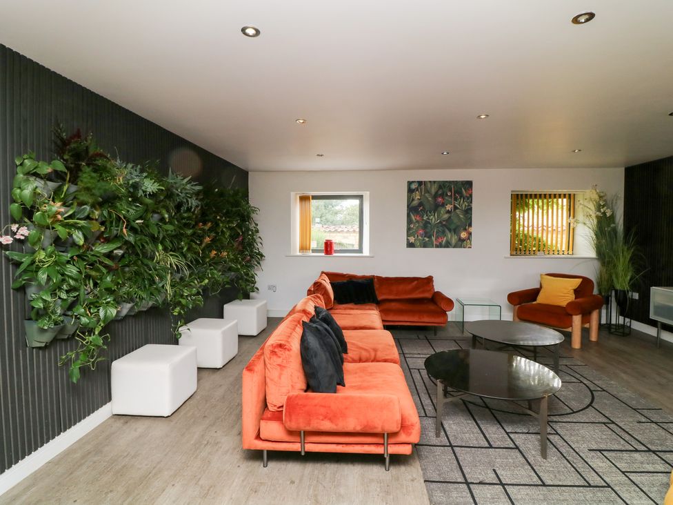 A living room with a sofa, coffee table, and plants at Hayloft in Scampton