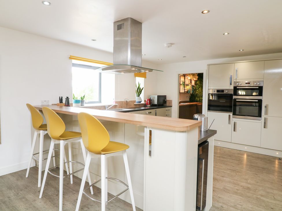 A kitchen with bar stools and a kitchen island at Hayloft in Scampton