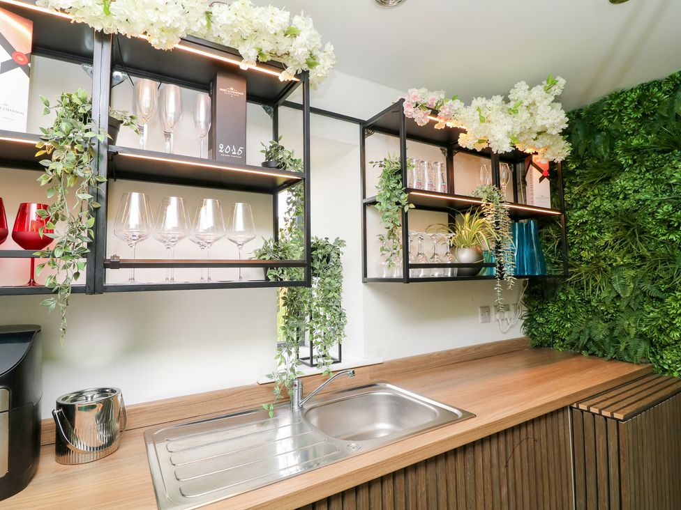 A kitchen with a sink and glassware on shelves at Hayloft in Scampton