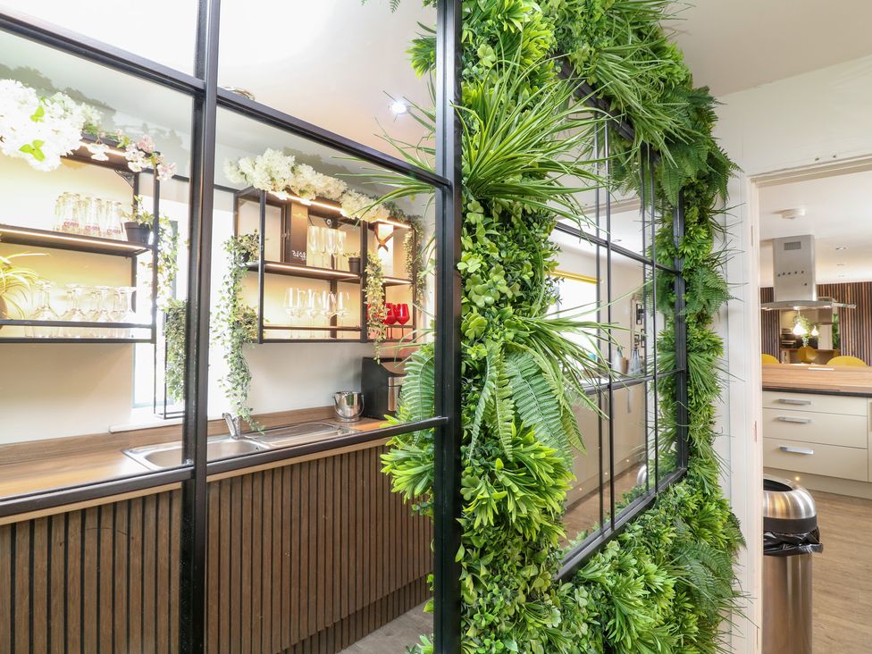 A kitchen with shelving, glassware, plants and a sink at Hayloft in Scampton