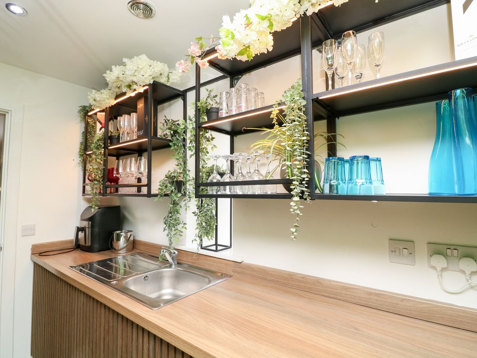 A kitchen with a sink and shelves containing glasses at Hayloft in Scampton