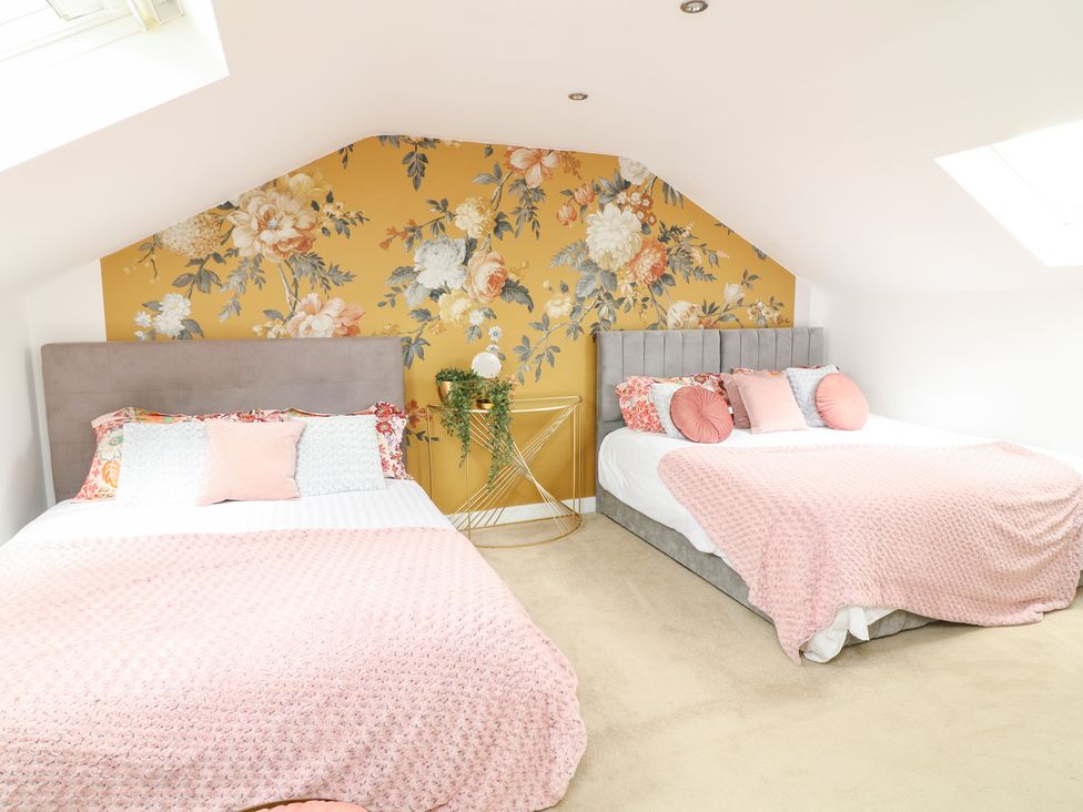 A bedroom with two beds and floral wallpaper at Hayloft in Scampton