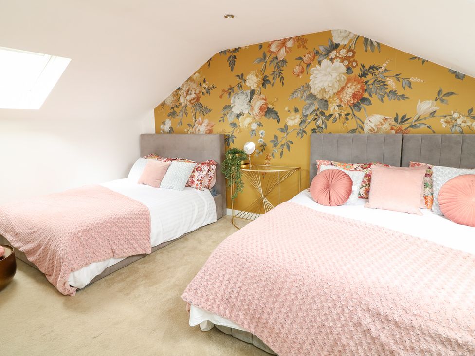 A bedroom with two beds and a floral wall at Hayloft in Scampton