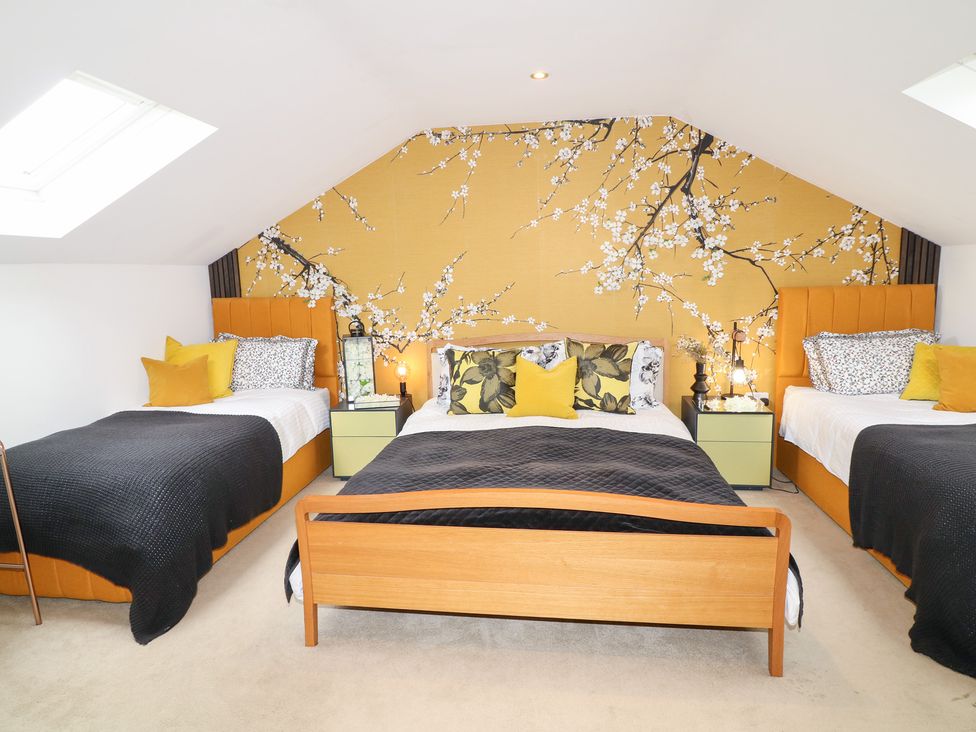 A bedroom with three beds and floral wall decor at Hayloft in Scampton
